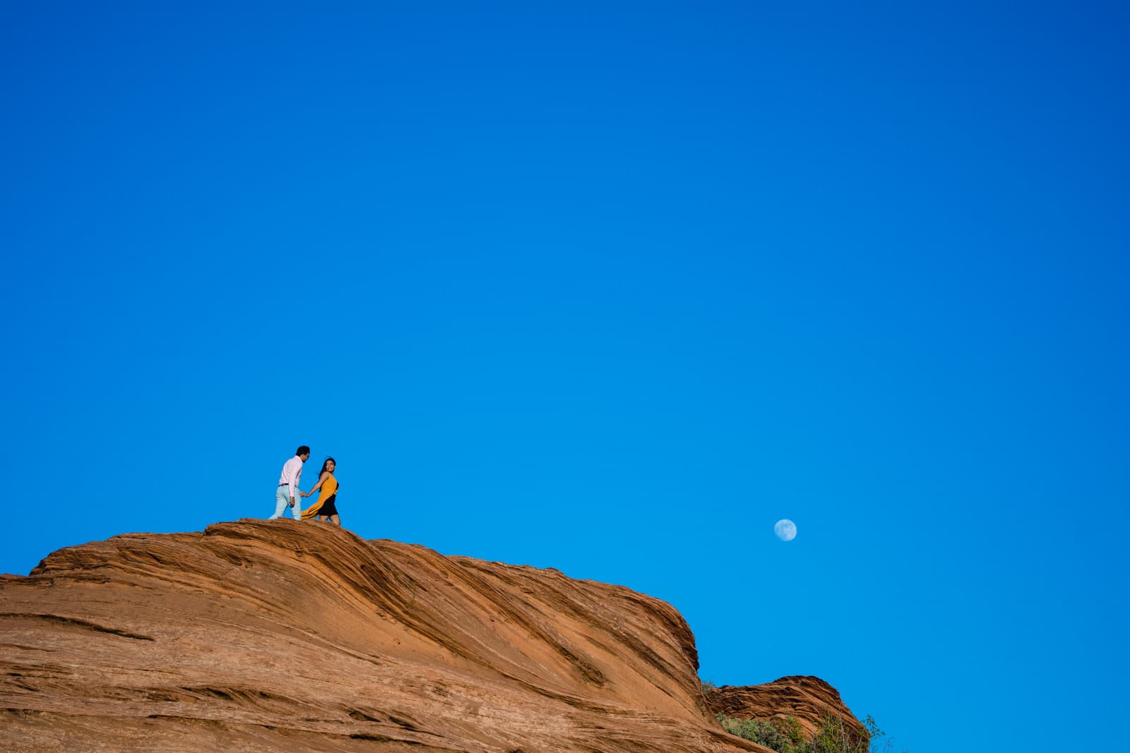 A couple walks a red sandstone ridge near Page, Arizona
