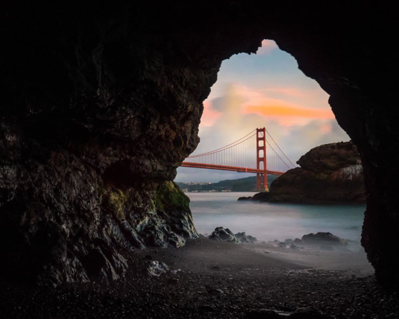 The Golden Gate Bridge framed through a sea cave at Kirby Cove